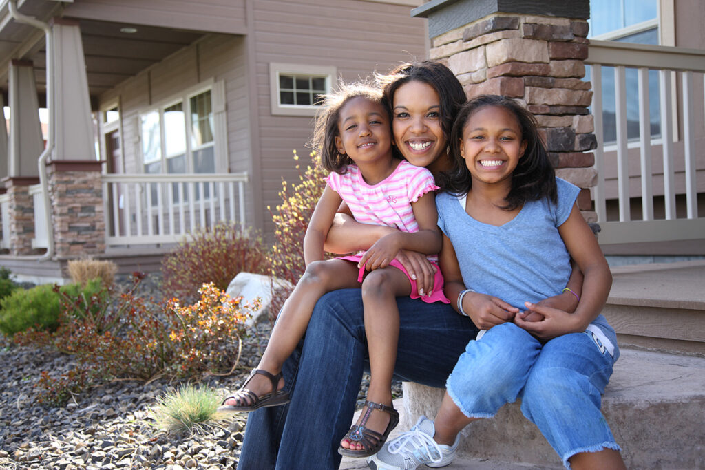 Mom and two daughters in from of new home